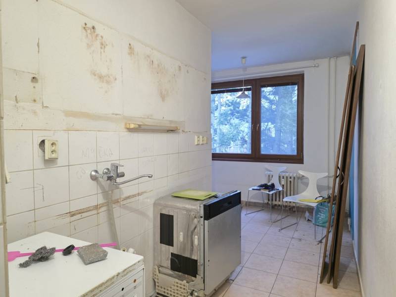A kitchen in a 2-room apartment with old furnishings and a floor with a wooden decor.