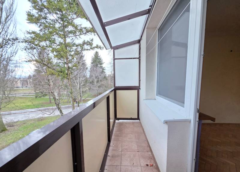 Balcony in a 2-room apartment with a view of greenery, tiled floor.
