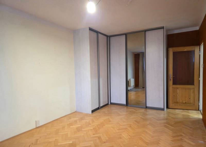 A room with a wooden decor floor, a built-in wardrobe, and doors in a 2-room apartment.