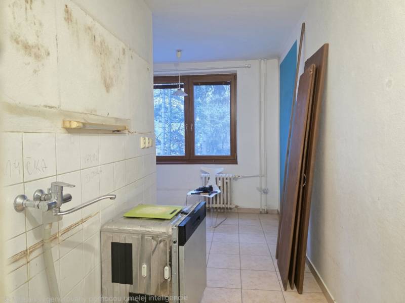 Unfurnished kitchen in a 2-room apartment with light floor tiles and a window.