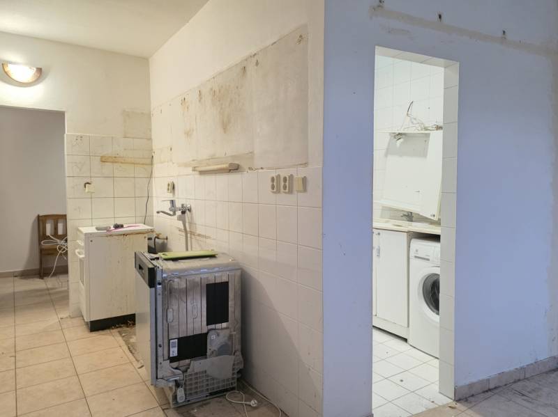 Incomplete kitchen and laundry room in a 2-bedroom apartment with ceramic tiles.