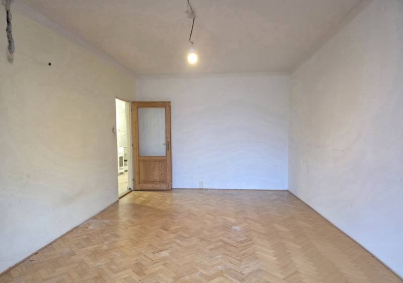 A room in a 2-room apartment with a wooden decor floor and open doors.