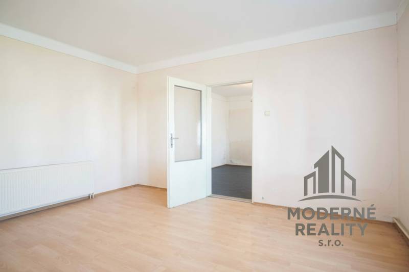 A room in a family house with white walls and a wooden decor floor.