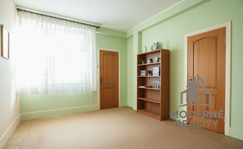 A room in a family house with a library, green walls, and doors with a wooden decor.