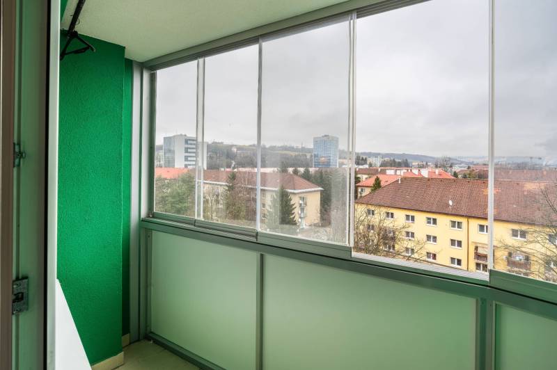 A glazed balcony with a view of the buildings on SNP Avenue in Banská Bystrica.