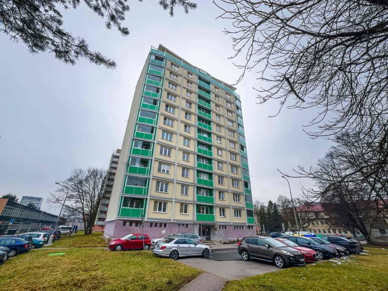 High-rise residential building on Trieda SNP in Banská Bystrica with a parking lot in the foreground.