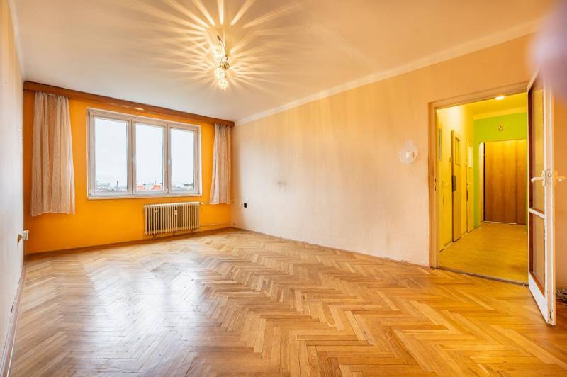 A spacious room with a wood-patterned floor and an orange wall in a 2-room apartment.