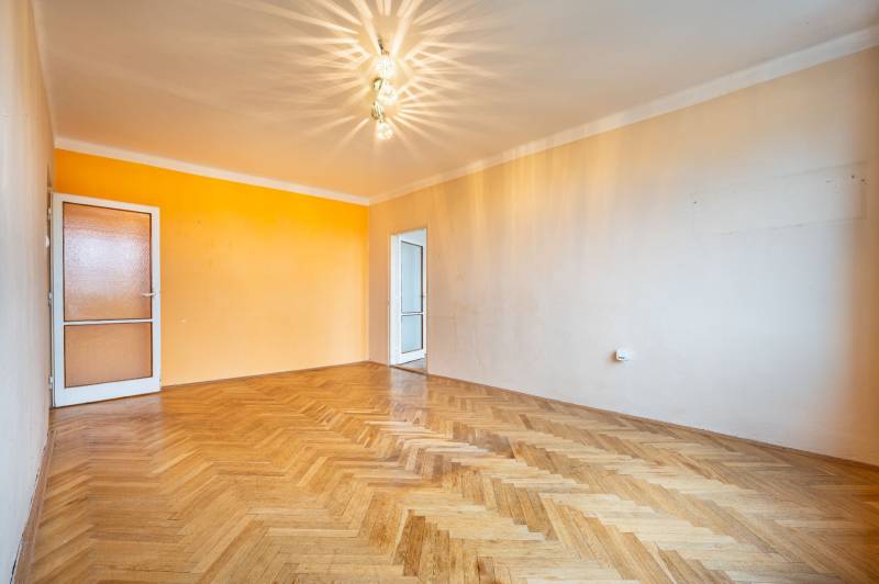 A bright room with wood-patterned flooring in a two-room apartment with colorful walls.