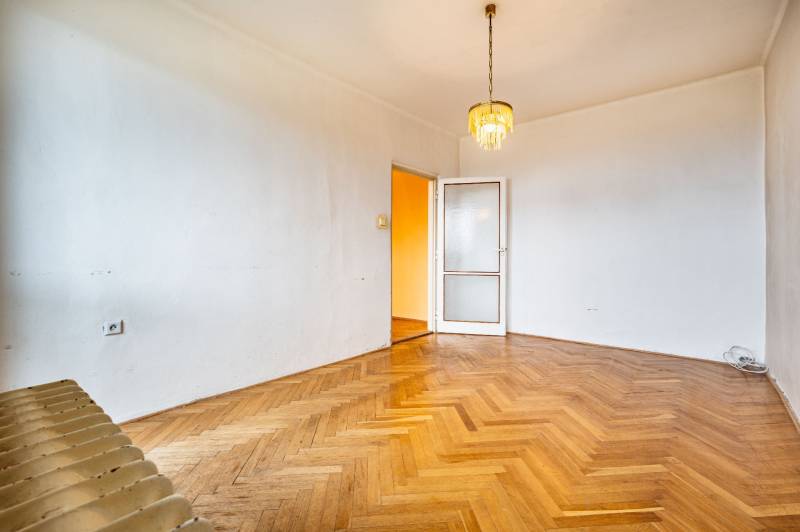 An empty room with a chandelier, doors, and a wooden-patterned floor, 2-room apartment.