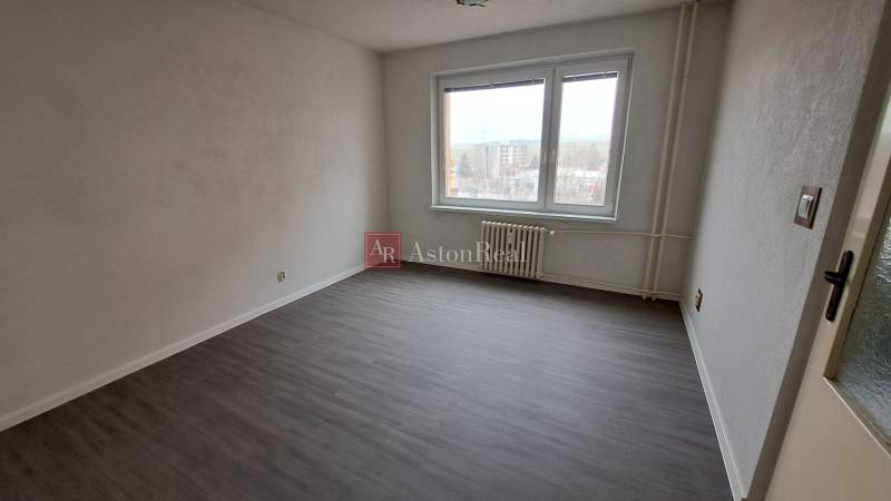 A room with a wooden decor floor in a studio apartment, an empty room with a window.
