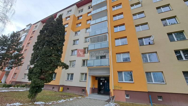 A seven-story apartment building on Za dráhou Street in Ružomberok surrounded by trees.