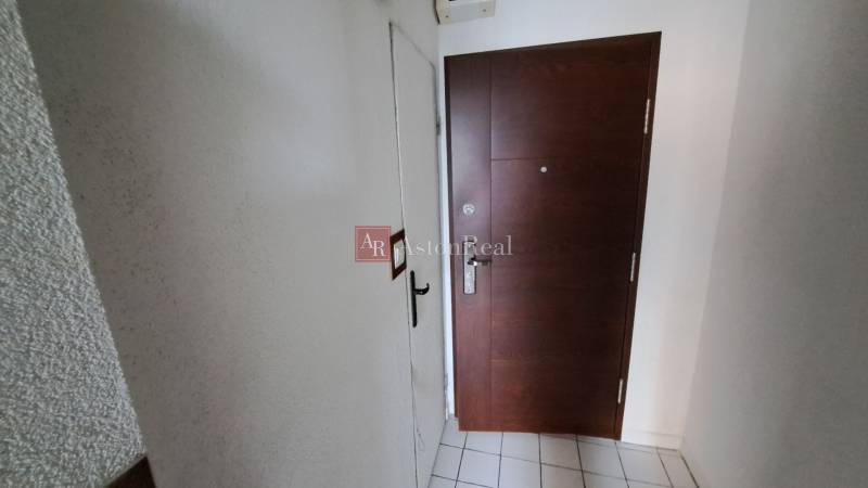 The entrance door to a one-room apartment with tiles and white walls.