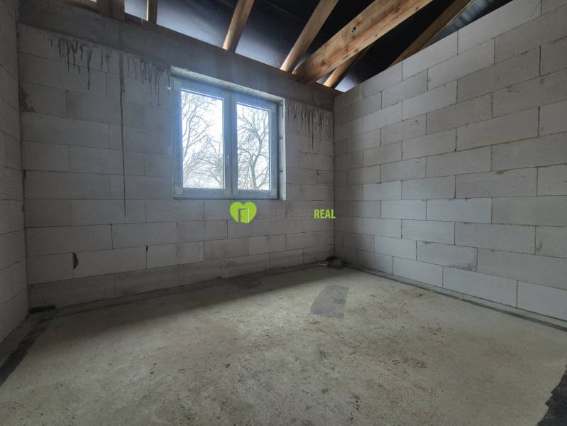 Interior of a family house with raw walls, a window, and a concrete floor.