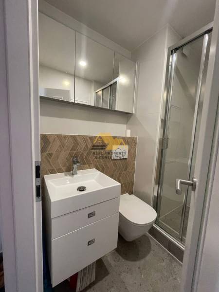 Bathroom in a studio apartment with a sink, shower, and mirrored cabinet.