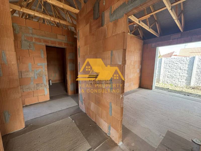 An unfinished family house with a view of walls without plaster and a wooden roof structure.