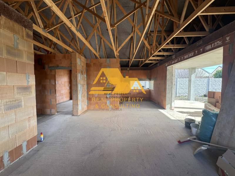 Interior of a family house under construction with exposed brick walls and a wooden ceiling.