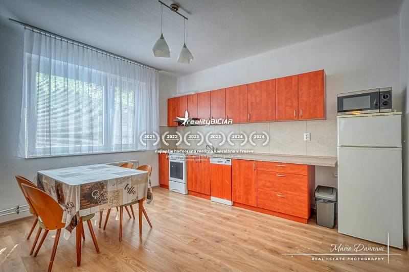 A kitchen in a family house with an orange kitchen unit, a dining table, and a bright interior.
