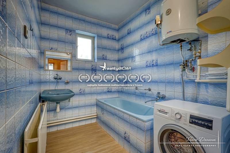 A bathroom with a shower and a washing machine in a family house. Blue tiles and a white boiler.