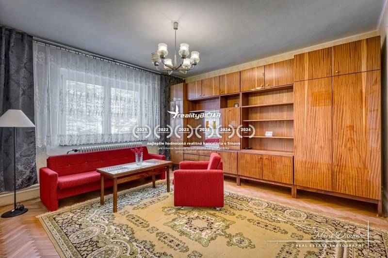 Living room in a family house with red sofas, a chandelier, and a wooden wall unit.
