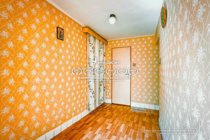 A room in a family house with orange wallpaper and parquet flooring.