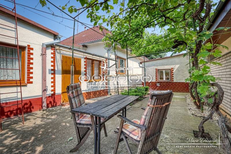 A garden of a family house in Trnava with a wooden table and chairs in the yard.