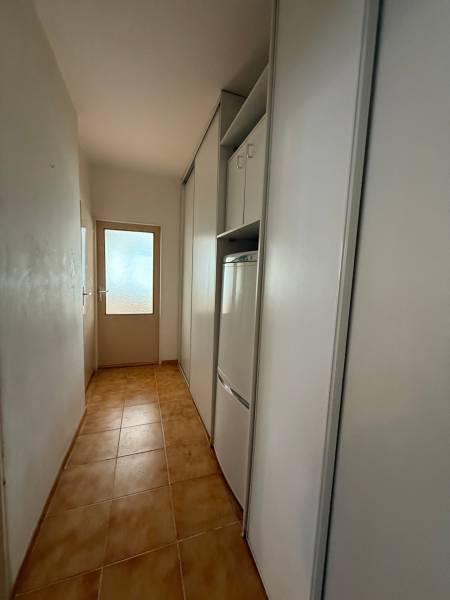 A narrow hallway with storage space and a tiled floor in a 3-room apartment.