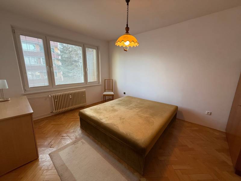 Bedroom in a 3-room apartment with a window, bed, and floor with a wooden decor.