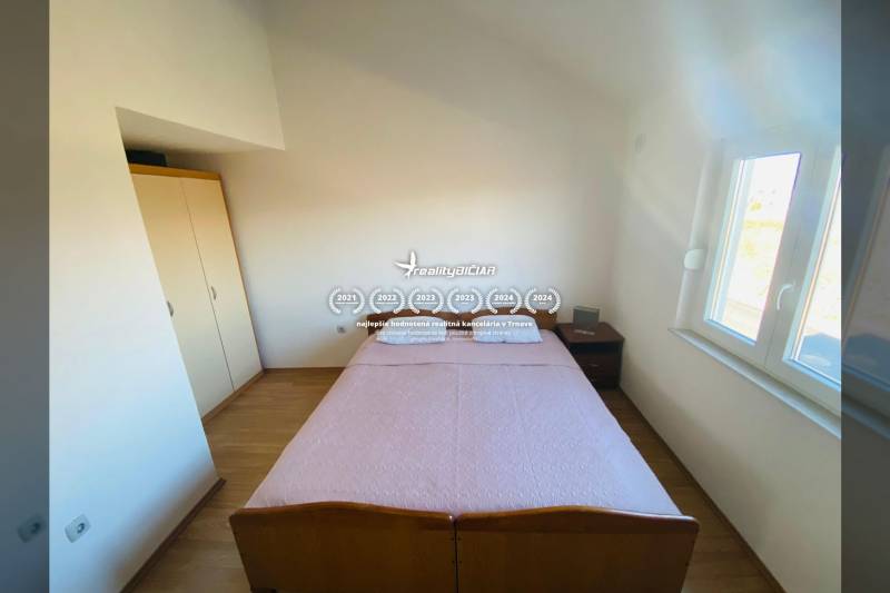 Bedroom in a family house with a bed, nightstand, and floor with wooden decor.