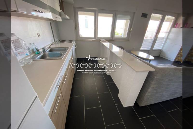 A kitchen in a family house with a dark wood-patterned floor and a bar counter.