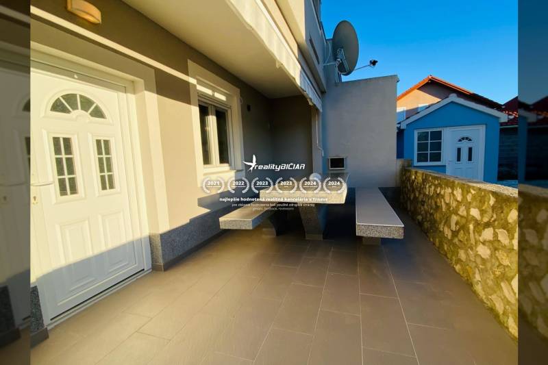 The family house in Nitra on Grbi Street has a terrace with a stone wall and a satellite dish.