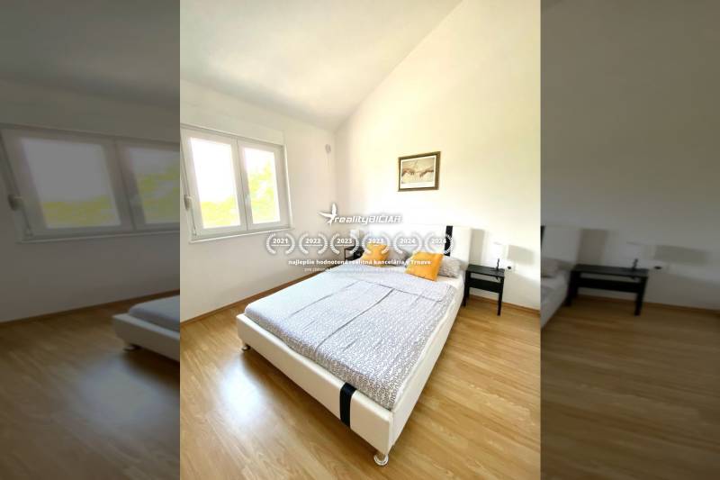 Bedroom in a family house with a wood-patterned floor, a bed, and a window.
