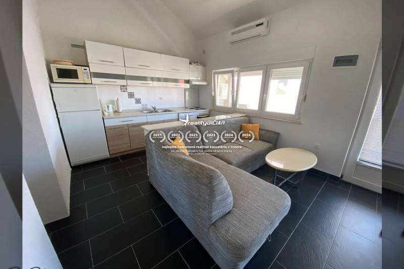 A kitchen with a corner sofa and a dining table, a family house, a floor with dark tiles.