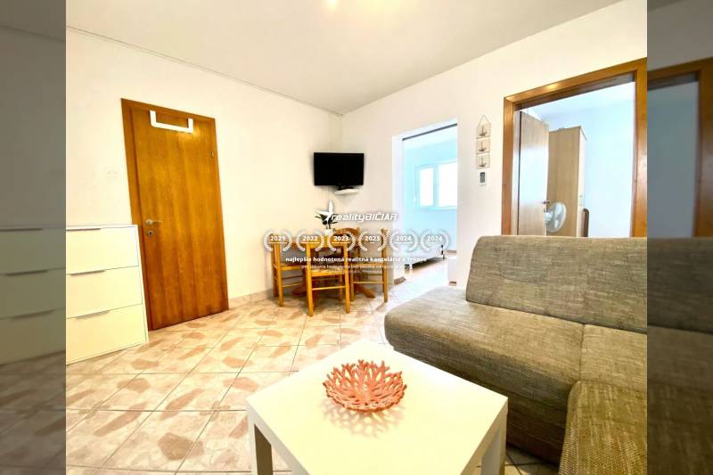 Living room in a family house with a sofa, a table, and a television on the wall.
