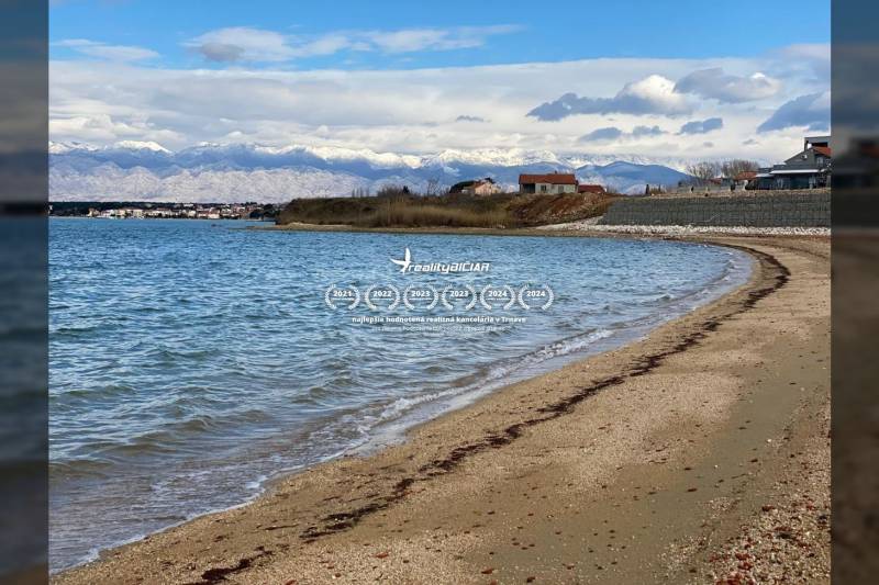 The coast in Nin with a sandy beach, view of houses and snowy mountains.