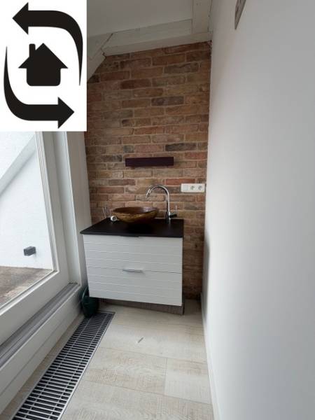 A small sink corner in a 4-room apartment with a brick wall and a wooden decor floor.