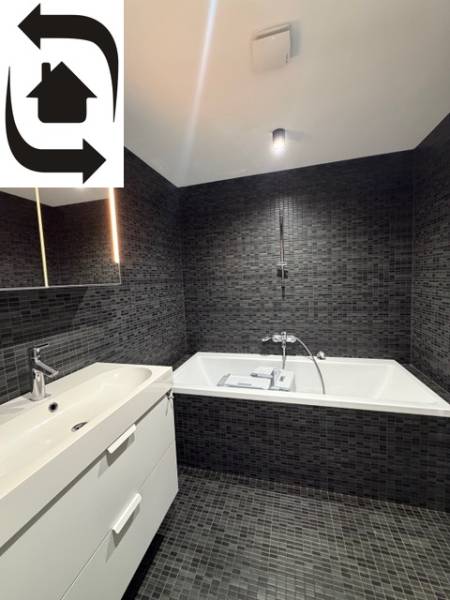 Elegant bathroom with dark tiles and a bathtub in a 4-room apartment.