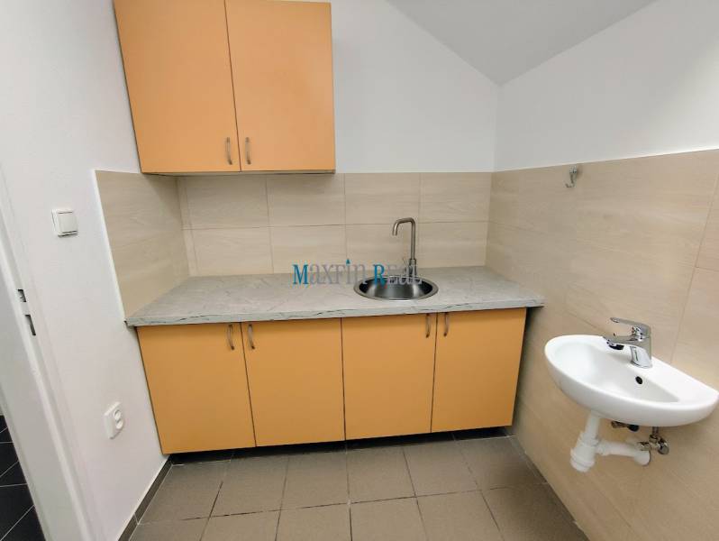 A kitchenette in commercial premises with yellow cabinets and a sink.