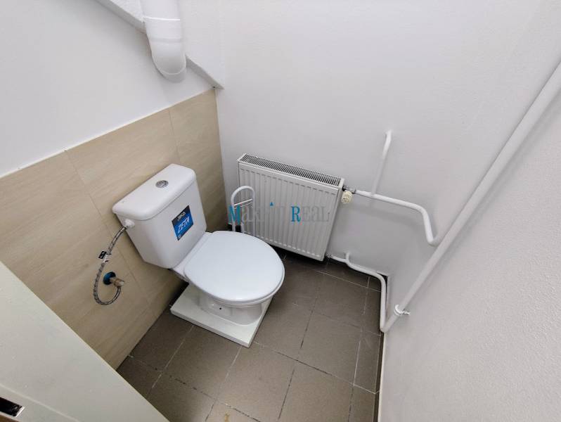 A restroom in commercial premises with a radiator and white walls.
