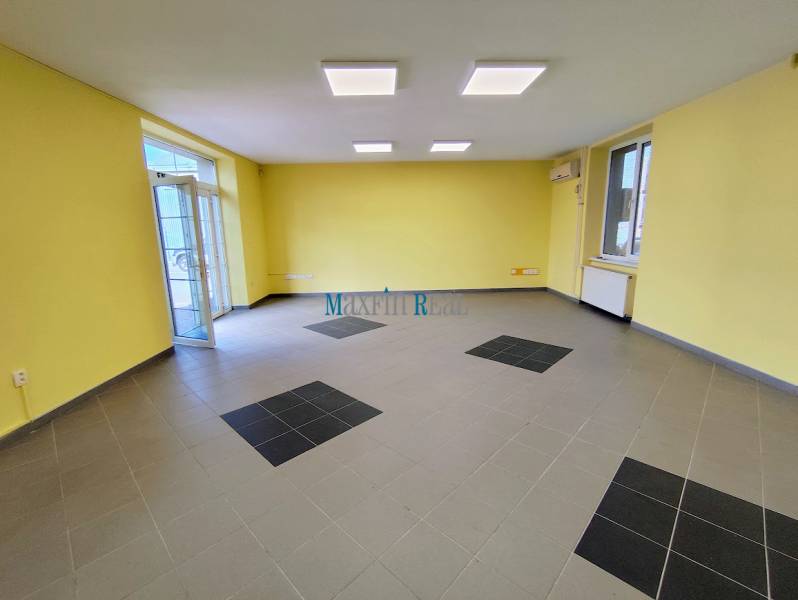 Commercial premises with yellow walls and gray tiles, light from windows, air conditioning.