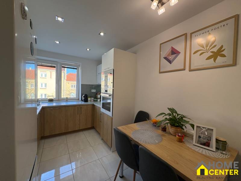 A kitchen in a 2-room apartment, light tiles, a table with decorations, pictures on the wall.