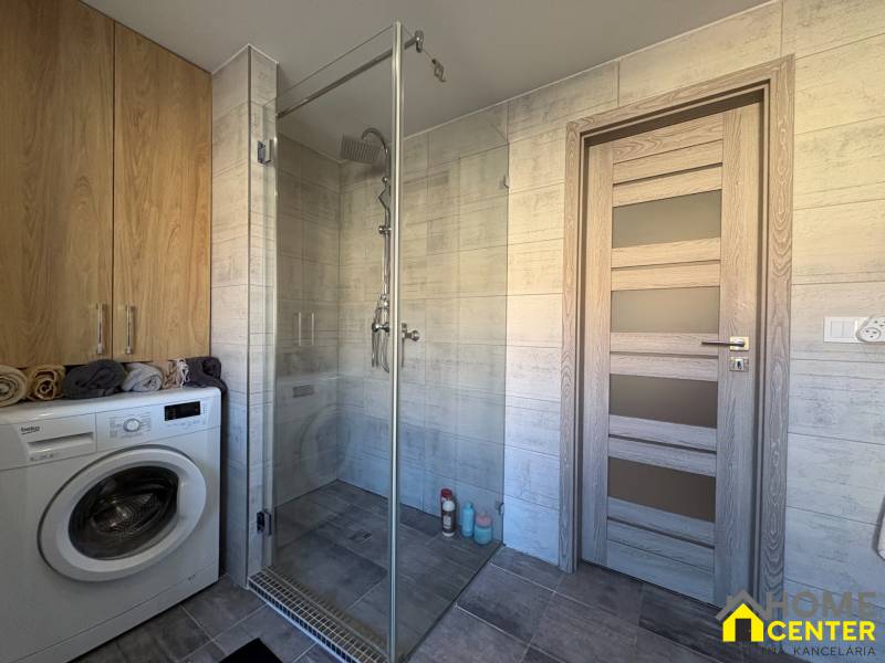 Bathroom in a 2-room apartment with a shower, washing machine, and storage space.