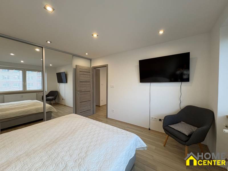 Two-room apartment with TV, wardrobe, and wooden decor flooring.