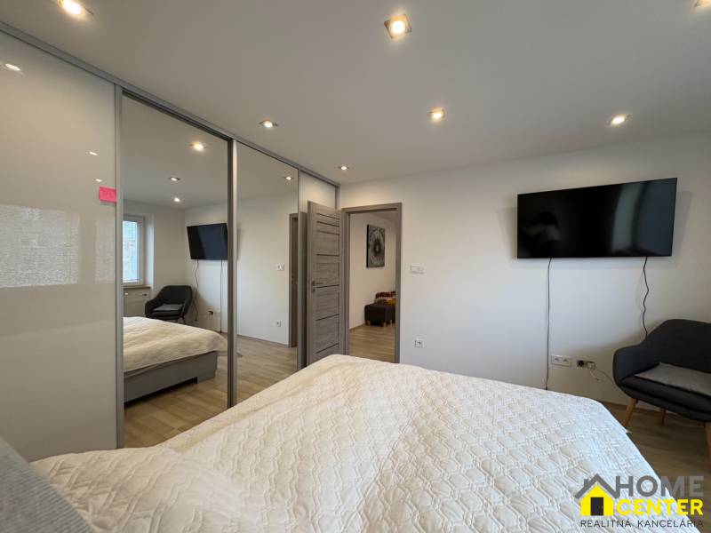 A bedroom in a two-room apartment with a television, a large wardrobe, and a floor with a wooden decor.