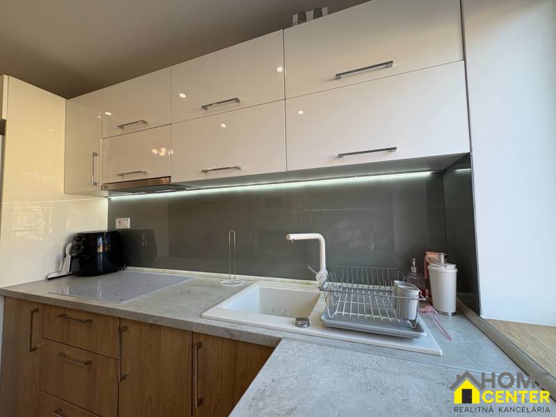 A kitchen in a 2-room apartment with light cabinets and lighting above the countertop.