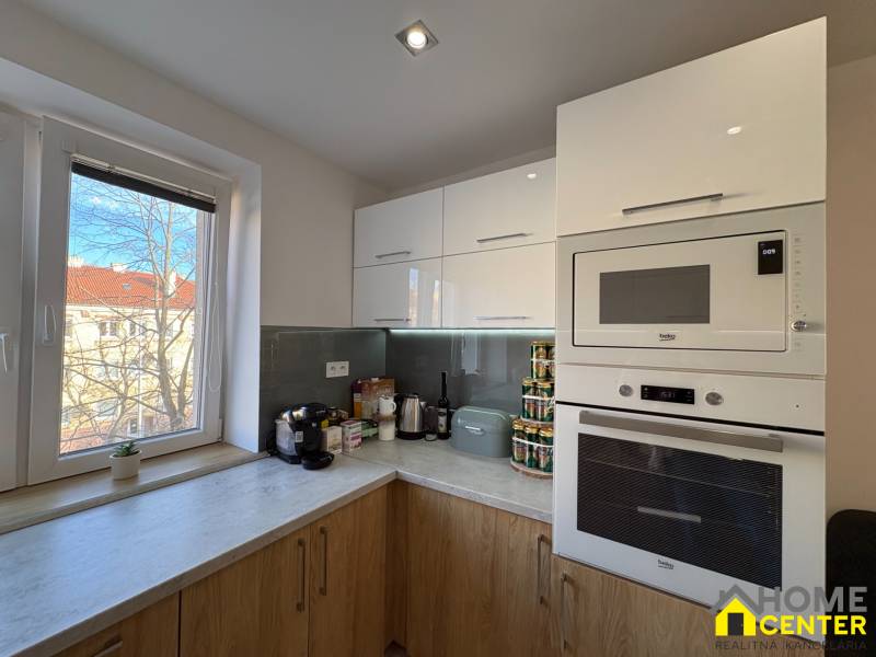 Kitchen in a 2-room apartment with white cabinets and a wooden decor floor.