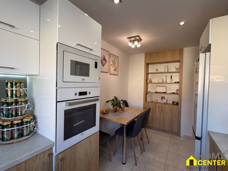 A kitchen in a 2-room apartment with modern appliances, a dining table, and storage cabinets.