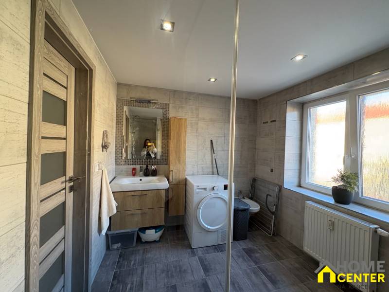 Bathroom in a 2-room apartment with a sink, washing machine, and wood-patterned tiles.
