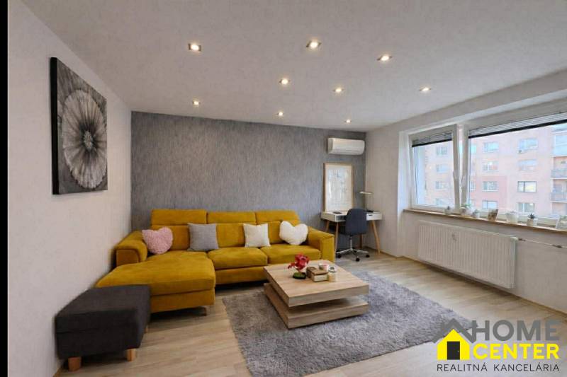 Living room in a two-room apartment with a sofa, wooden decor flooring, gray carpet.