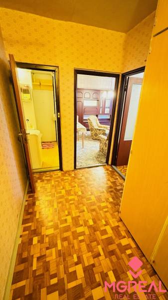 A corridor in a 2-room apartment with a wooden decor floor and doors to the rooms.