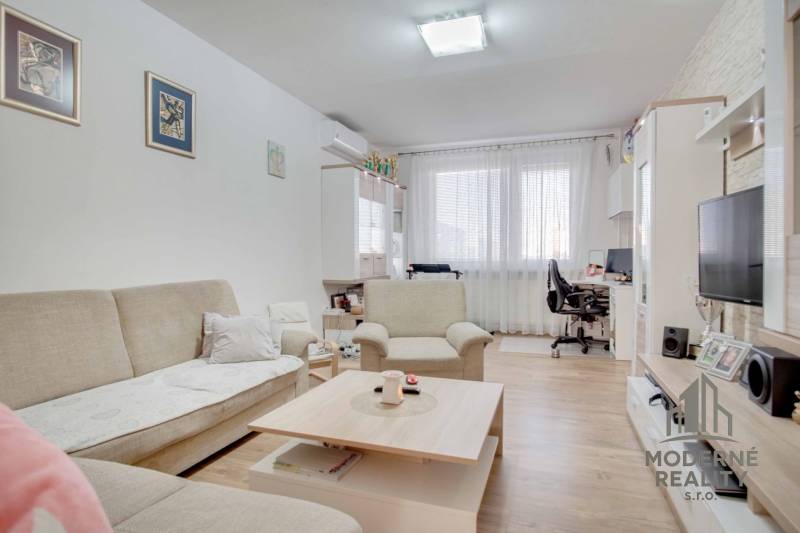 Living room in a three-room apartment with a wooden decor floor and comfortable seating.